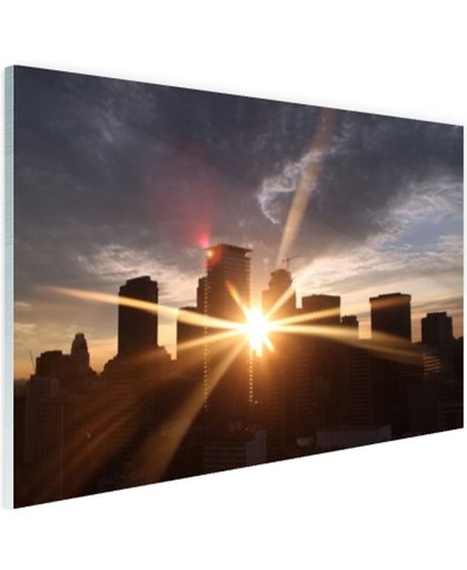 FotoCadeau.nl - Stralen ondergaande zon door gebouwen Glas 90x60 cm - Foto print op Glas (Plexiglas wanddecoratie)